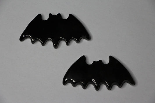Gold sheen obsidian crystals carved into bat shapes on a light background