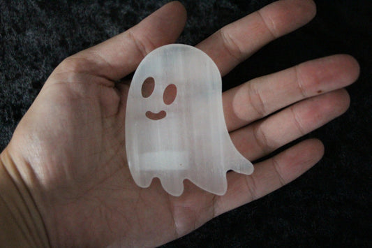 Hand holding a carved selenite ghost crystal, witch decor for ritual or altar