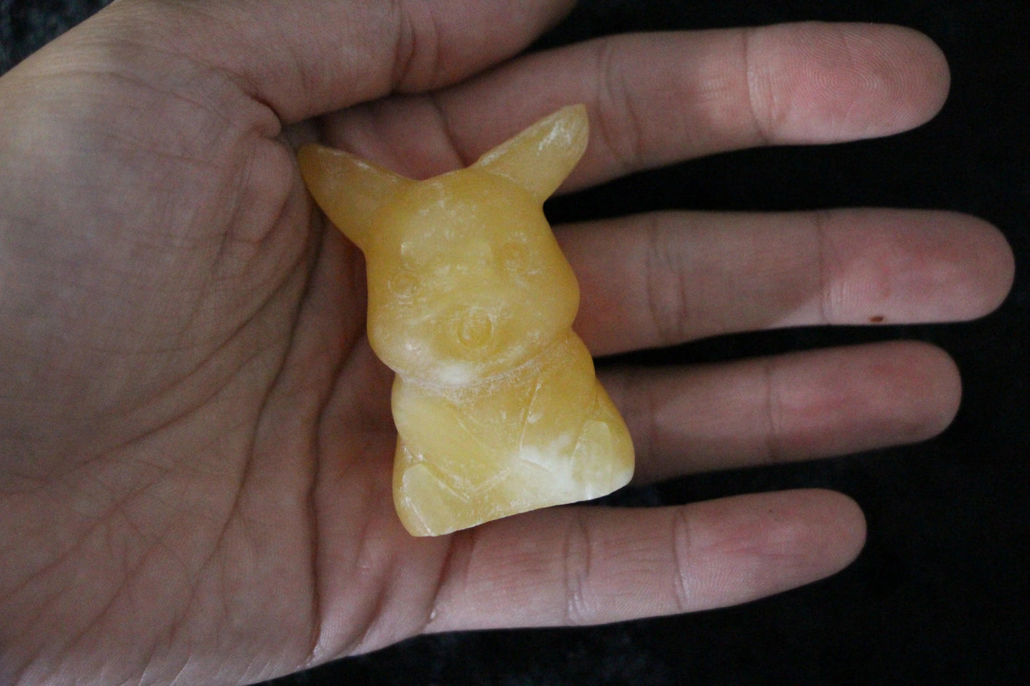 Hand holding yellow, hand-crafted animal-shaped soap on black background, Witches' Brew