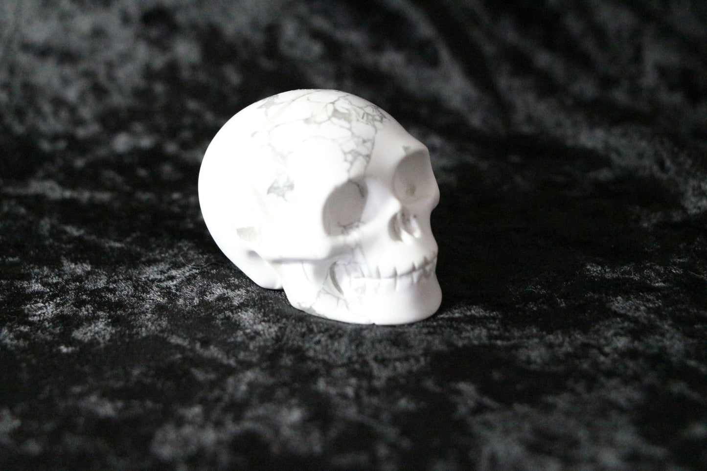 White howlite crystal skull on black velvet background, ritual decor