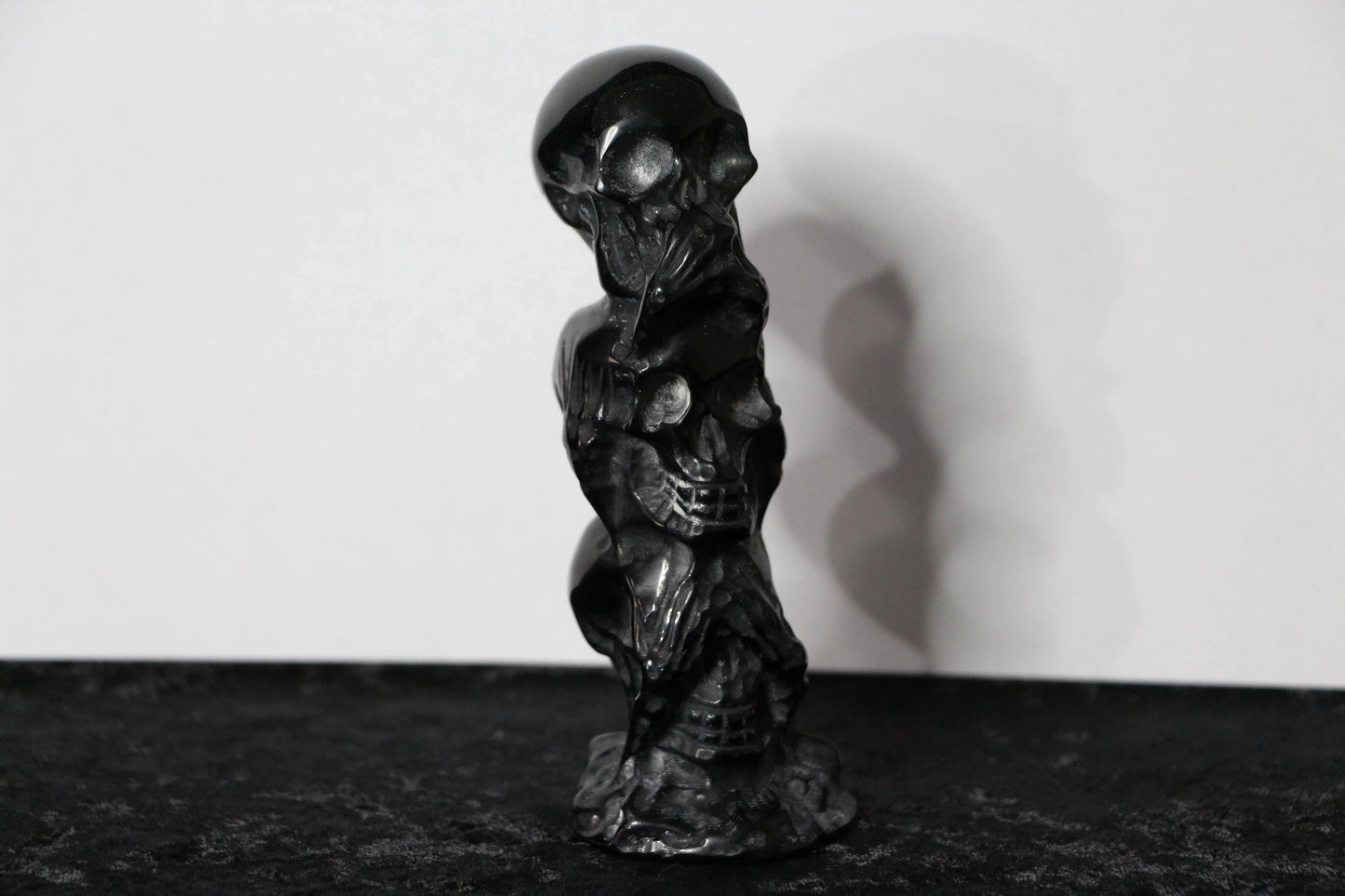 Hand-carved black obsidian skull statue on black surface, modern witch altar decor