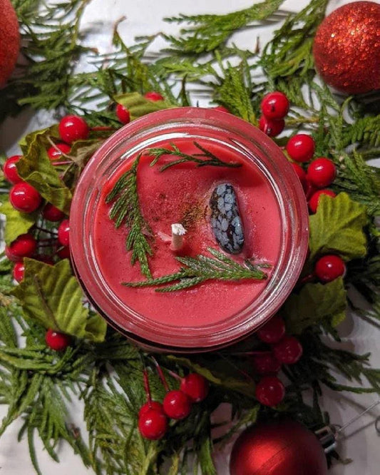 Hand-crafted red crystal candle with greenery, berries, and stone, festive witch decor.