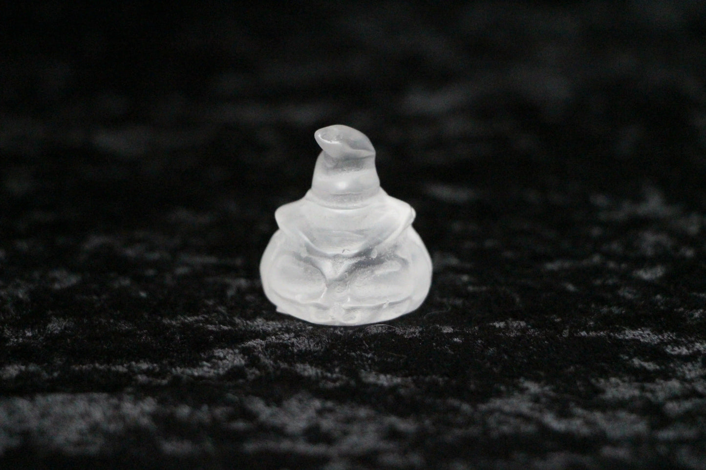 Clear quartz crystal witch figurine on black velvet background
