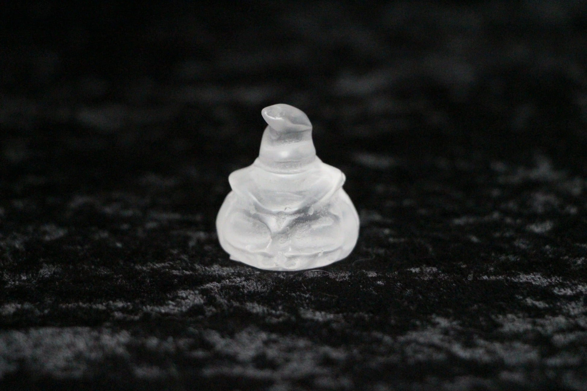 Clear quartz crystal witch figurine on black velvet background