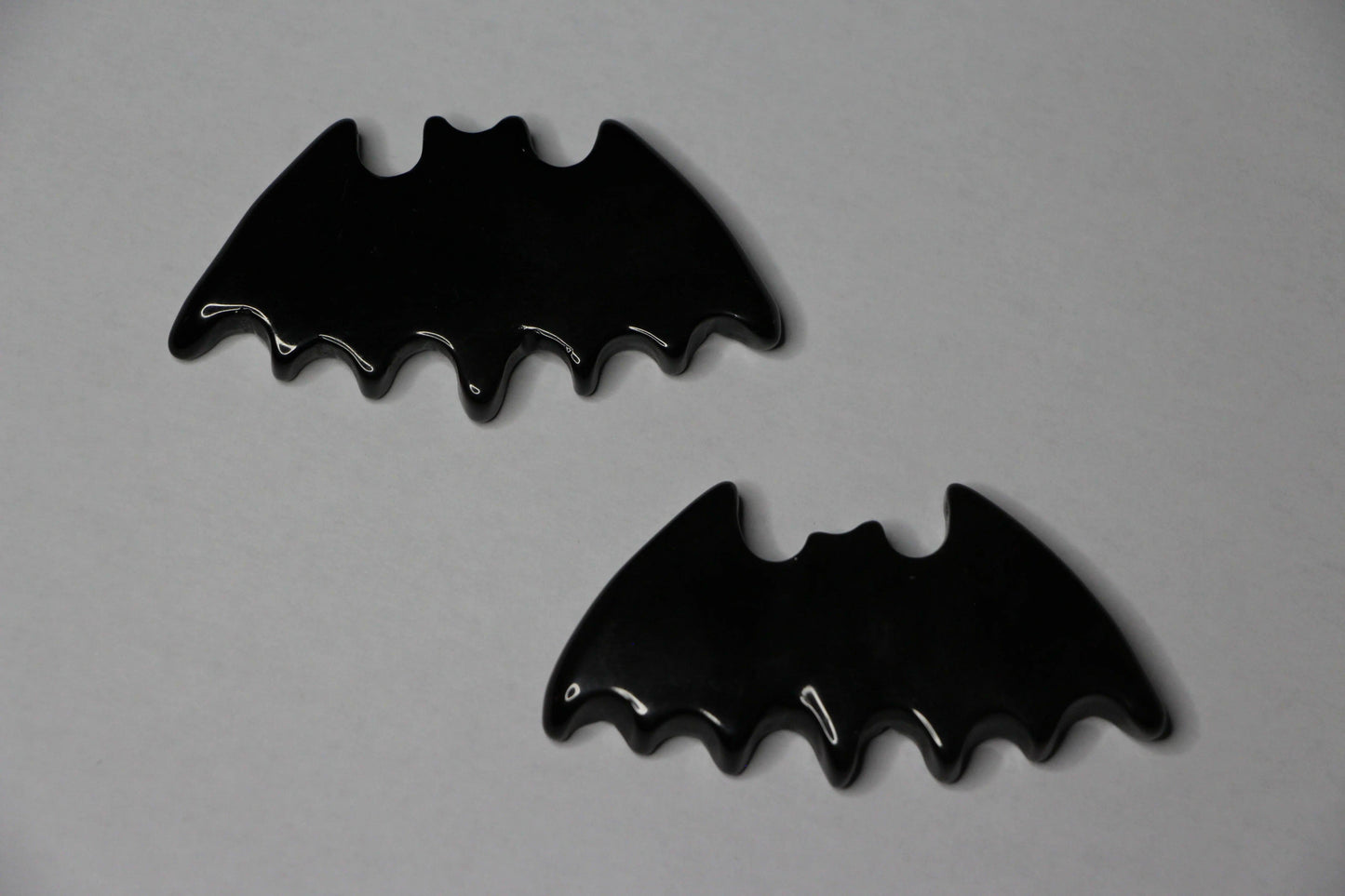 Gold sheen obsidian crystals carved into bat shapes on a light background