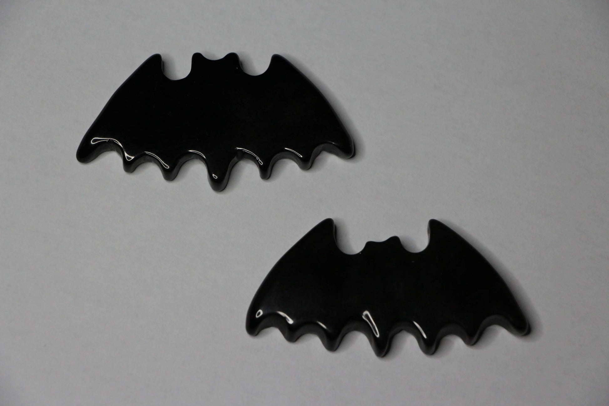 Gold sheen obsidian crystals carved into bat shapes on a light background