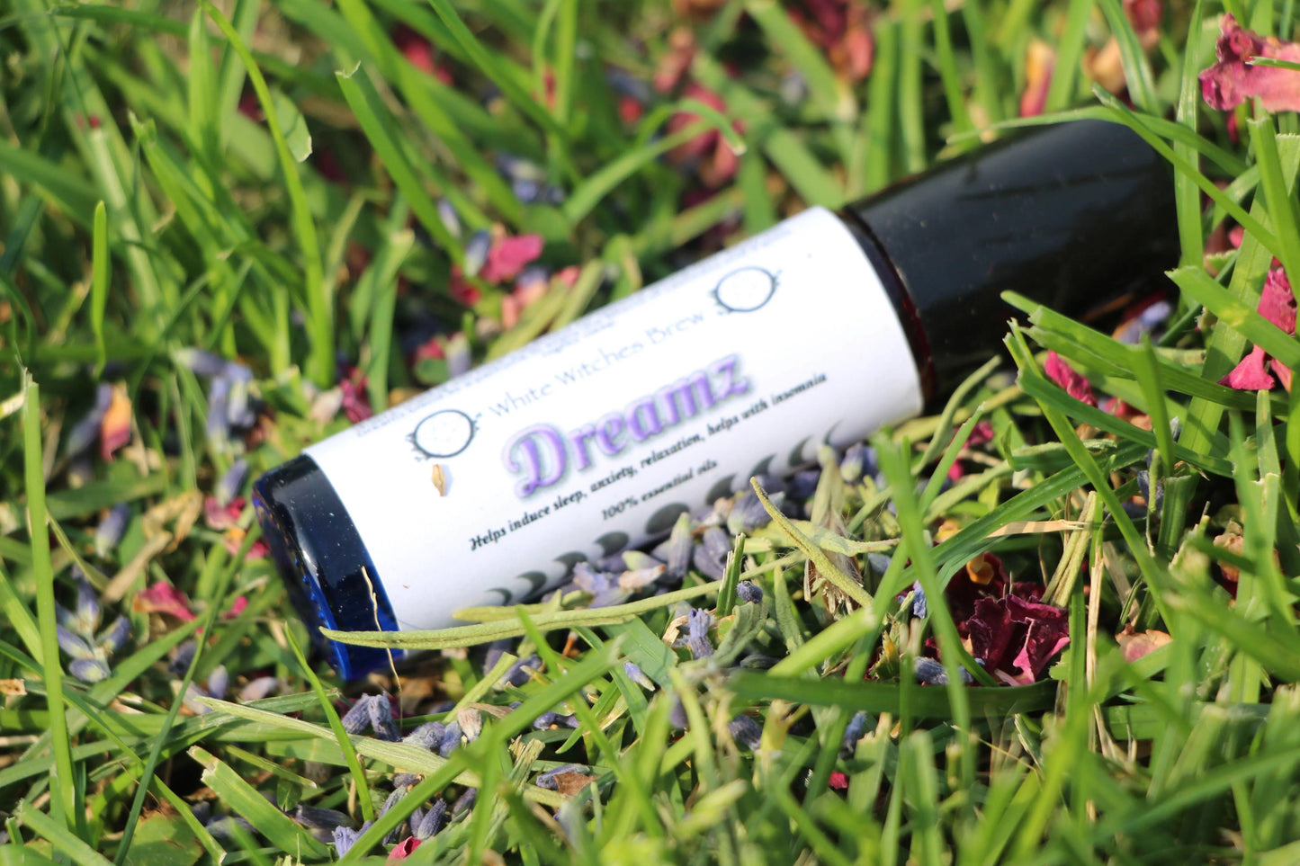 Dreamz essential oil roller for sleep and relaxation on green grass with flower petals