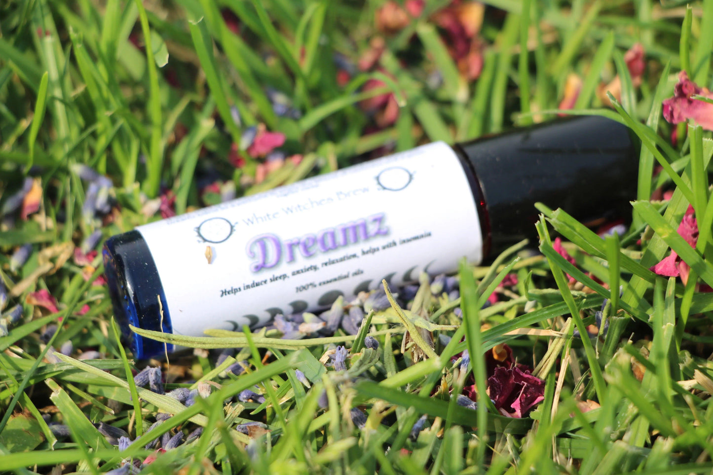 Dreamz essential oil roller on grass with flower petals, hand-crafted aromatherapy for sleep