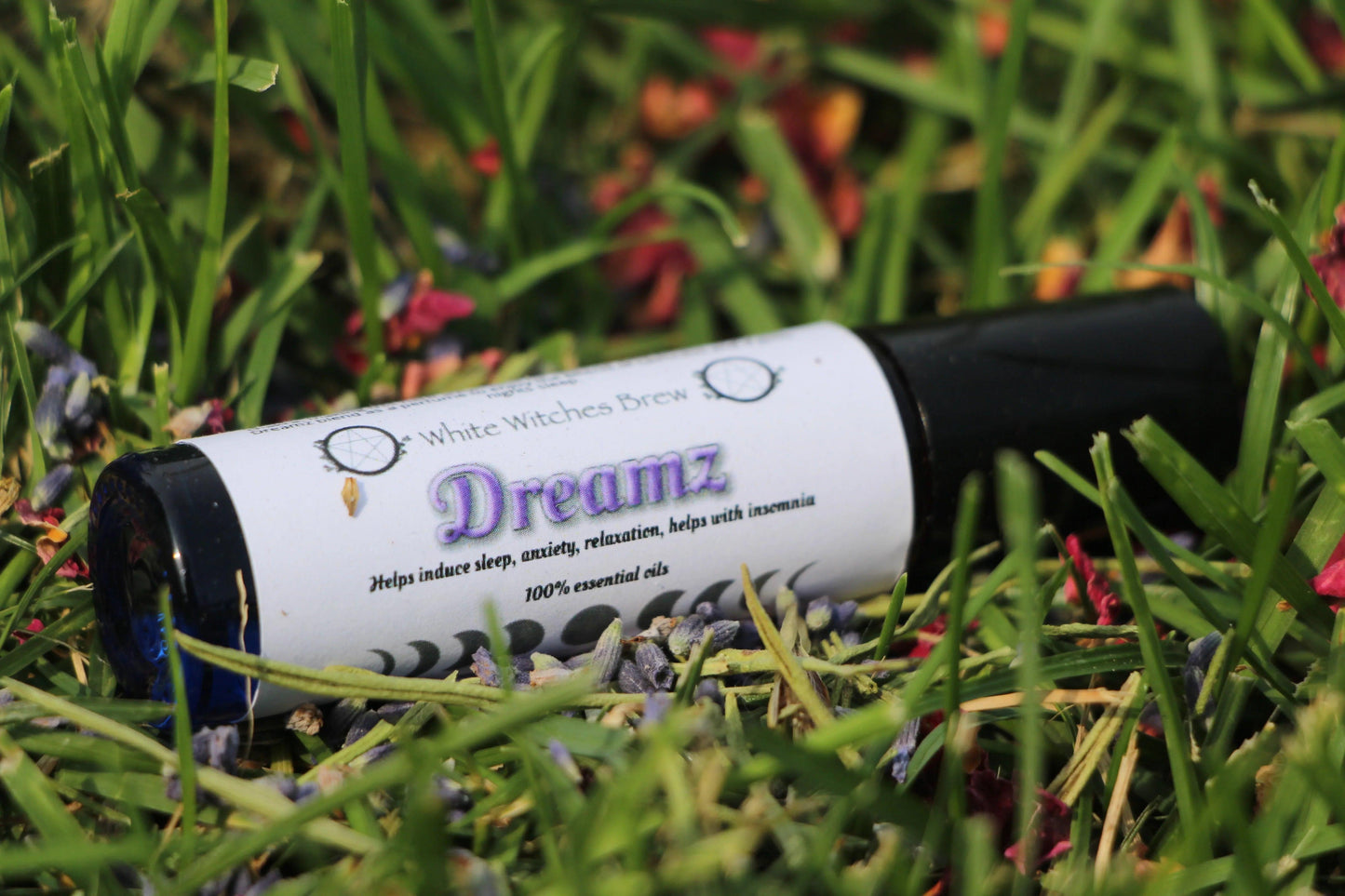 Dreamz essential oil roller from Witches' Brew on grass with flowers, handmade wellness product