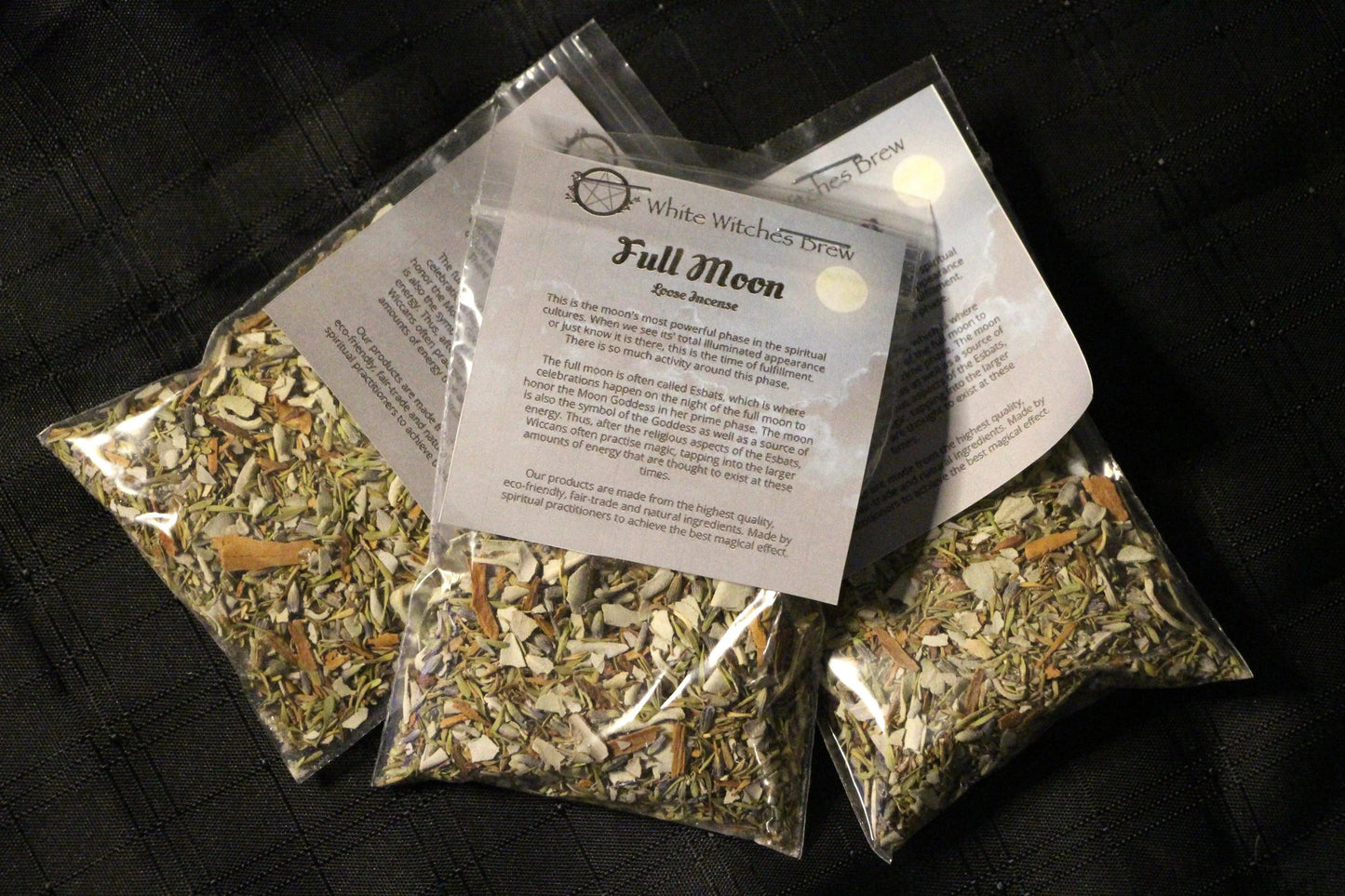 Three plastic bags of White Witches Brew Full Moon loose incense with herbal blends on black fabric
