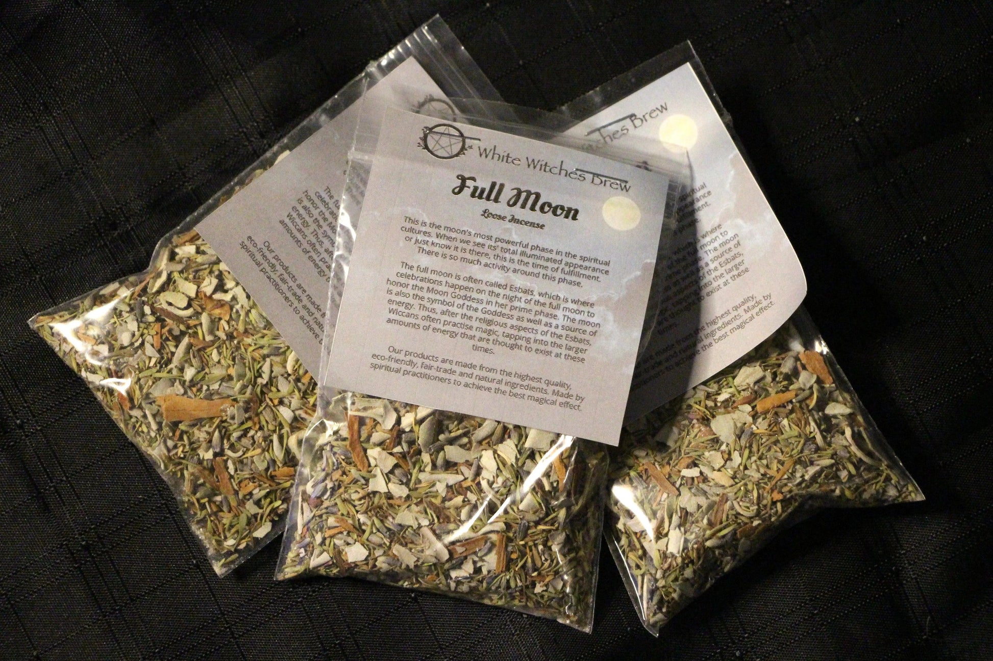 Three plastic bags of White Witches Brew Full Moon loose incense with herbal blends on black fabric