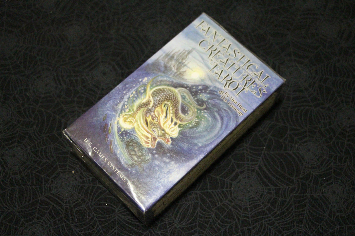 Fantastical Creatures Tarot deck box with dragon and turtle artwork on spiderweb tablecloth