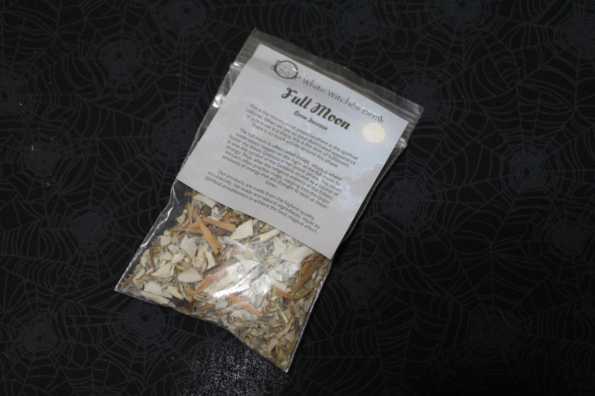 Full Moon loose incense blend in clear bag on black spiderweb-patterned cloth