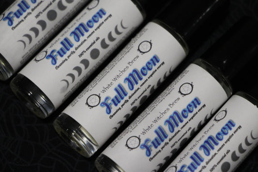 Roll-on bottles labeled Full Moon essential oils with moon phase symbols on black fabric