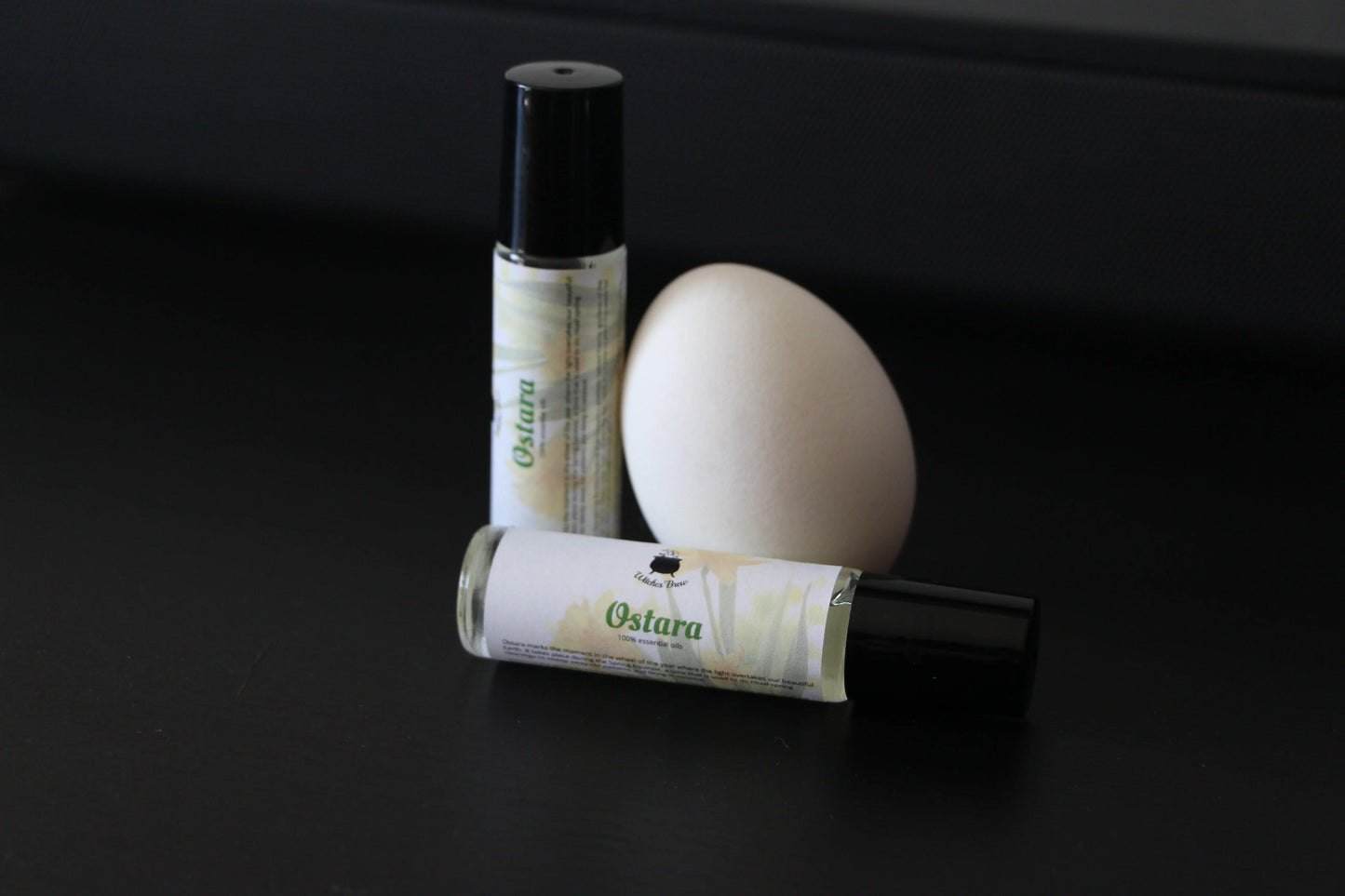 Ostara essential oil rollers by Witches' Brew with white egg on black background
