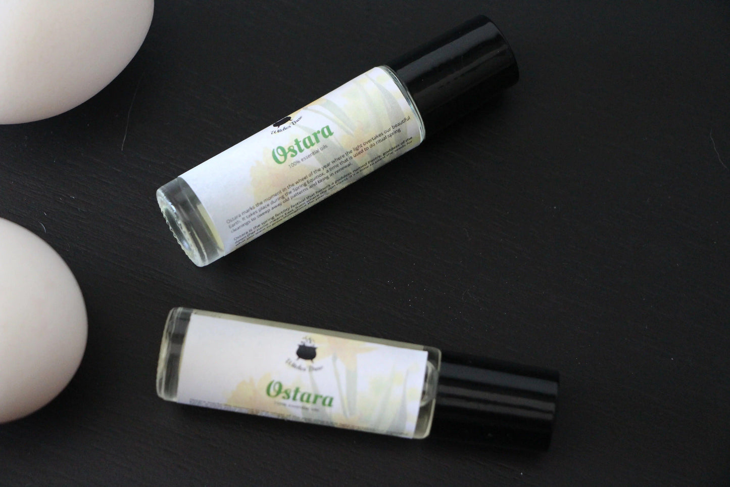 Ostara essential oil roller bottles on black surface, Witches' Brew ritual tool