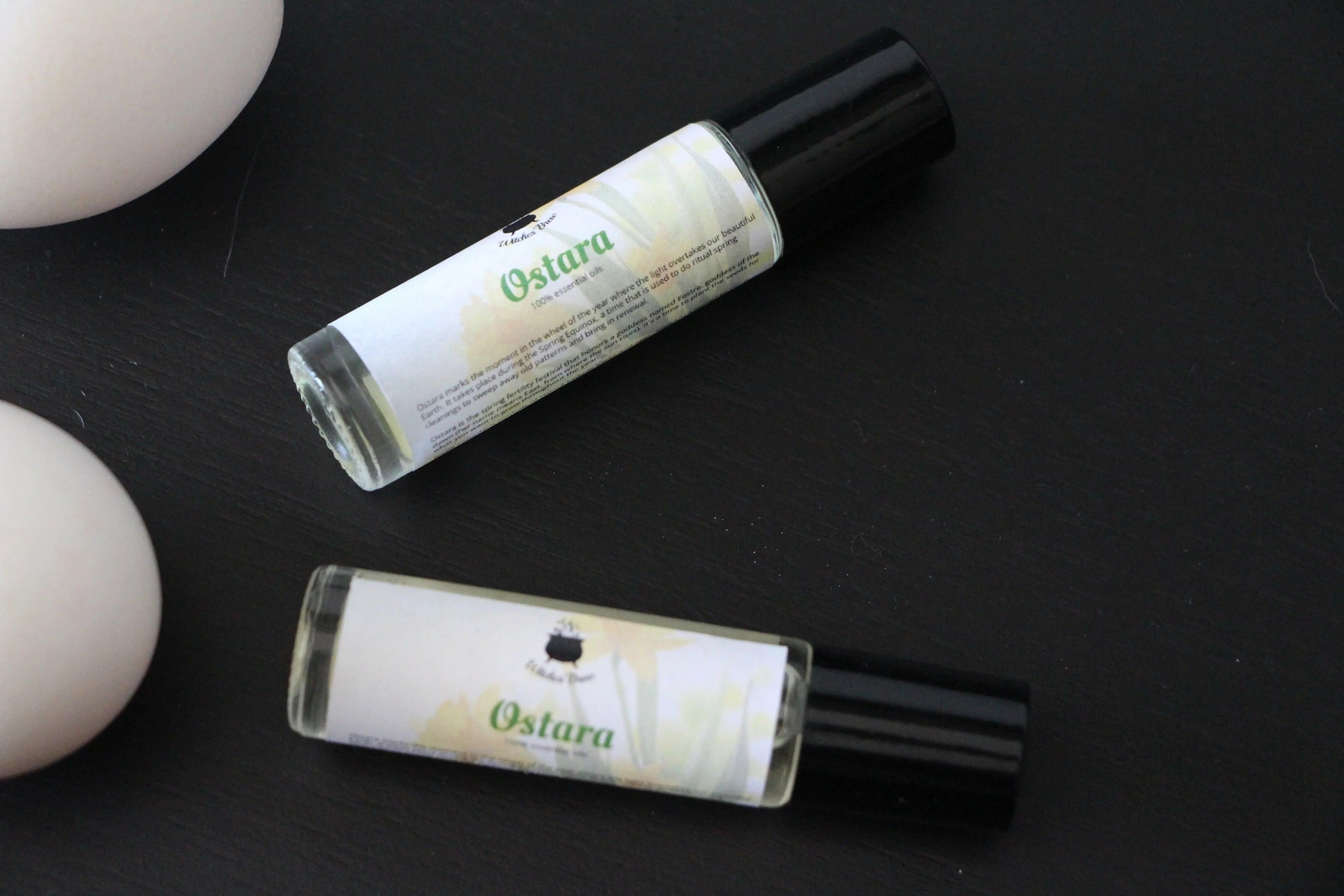 Ostara essential oil roller bottles on black surface, Witches' Brew ritual tool