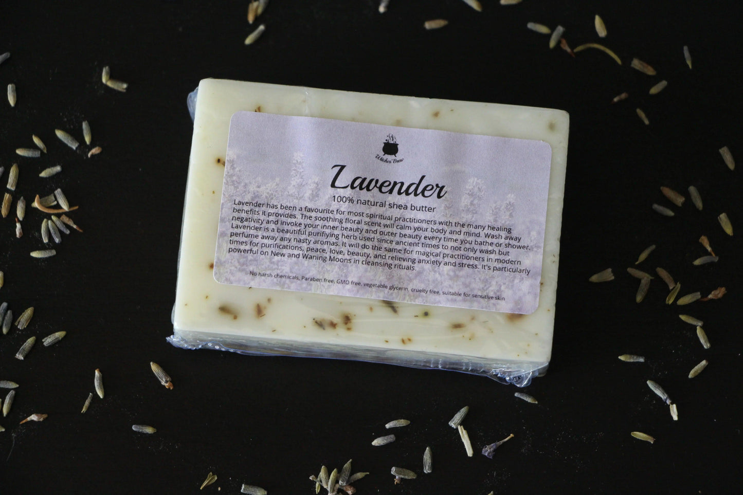 Lavender shea butter soap bar on black surface with scattered dried lavender buds