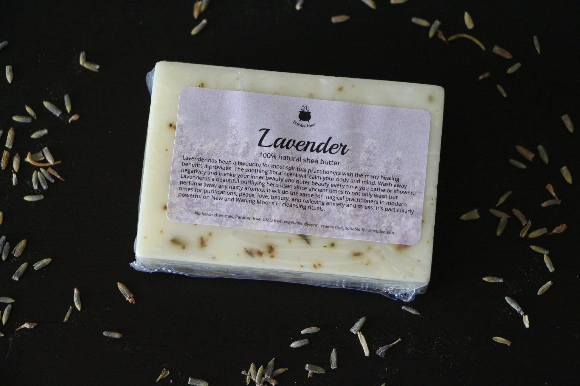 Lavender shea butter soap bar on black surface with scattered dried lavender buds