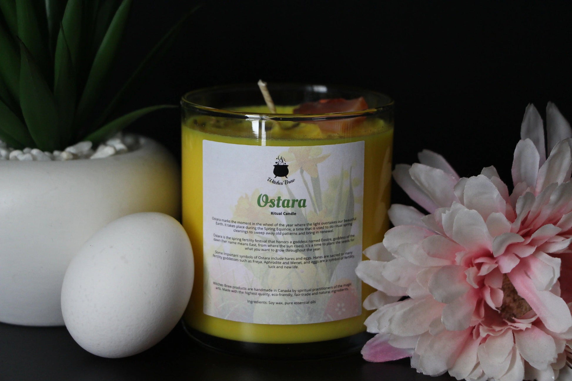 Ostara yellow crystal candle by Witches' Brew with white egg and pink flower, modern witch decor
