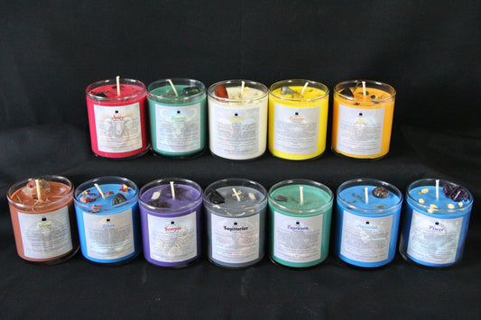 Hand-crafted zodiac crystal candles in colorful glass jars, arranged on a black background