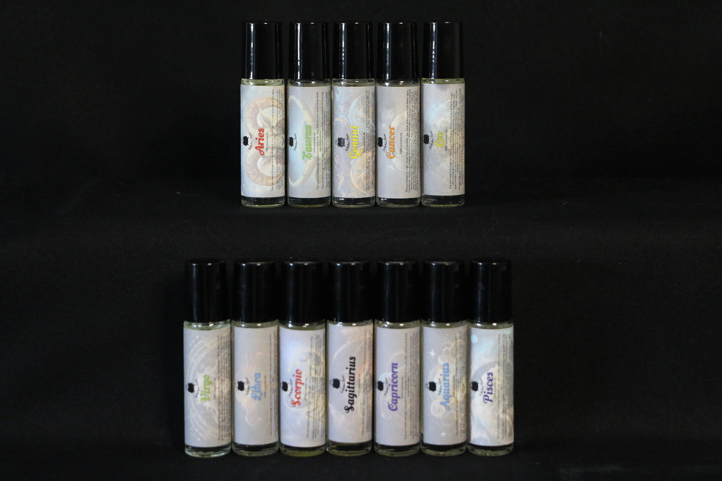 Zodiac essential oil roller bottles displayed on a black background, Witches' Brew ritual tools