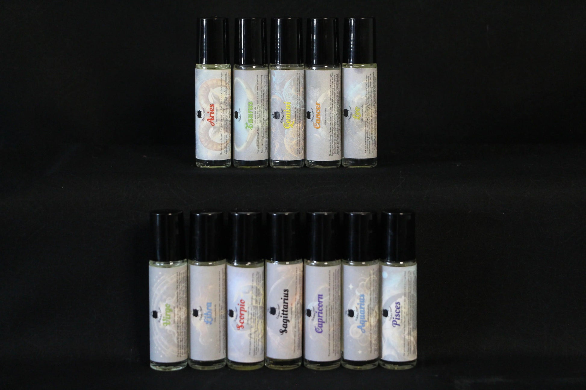 Zodiac essential oil roller bottles displayed on a black background, Witches' Brew ritual tools