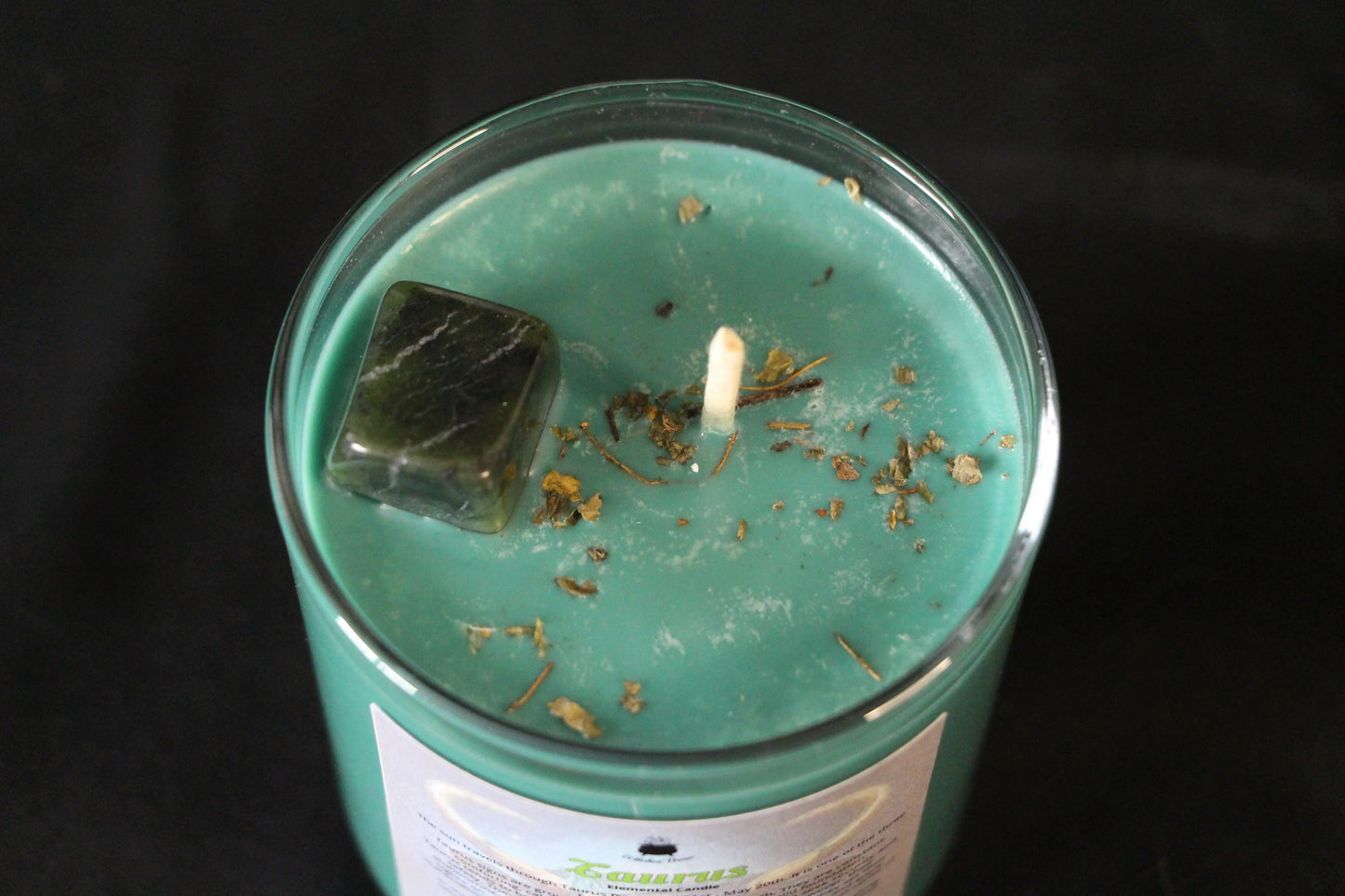 Green crystal candle with herbs in glass jar, sustainable hand-crafted witch decor