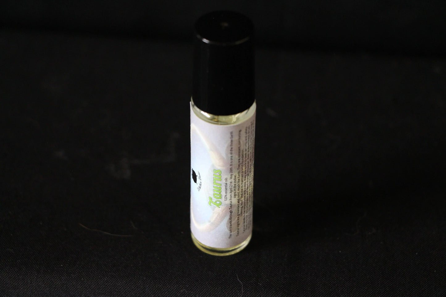 Hand-crafted Taurus essential oil roller bottle on black background, Witches' Brew