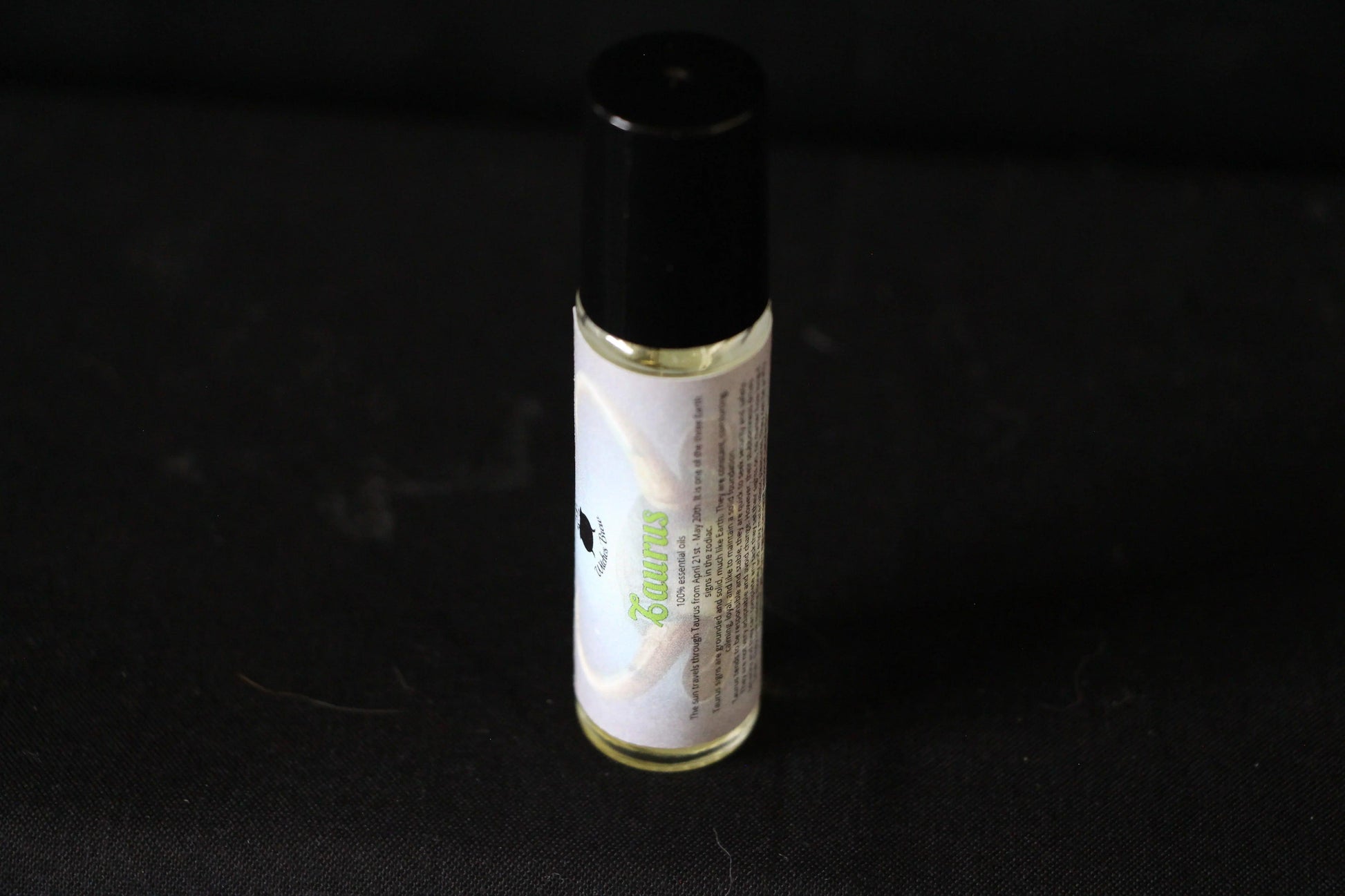 Hand-crafted Taurus essential oil roller bottle on black background, Witches' Brew