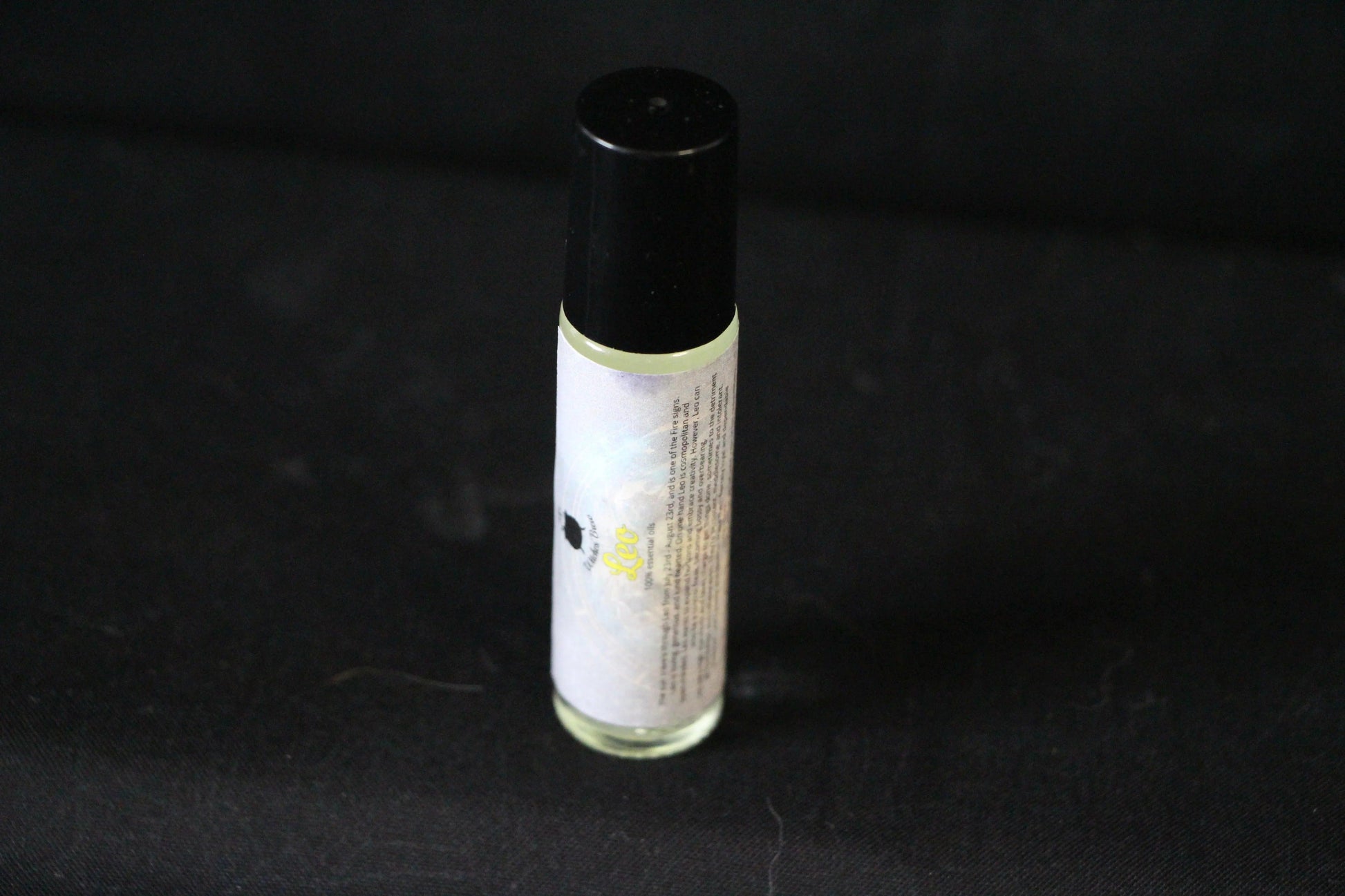 Hand-crafted essential oil roller bottle with label on black background, Witches' Brew