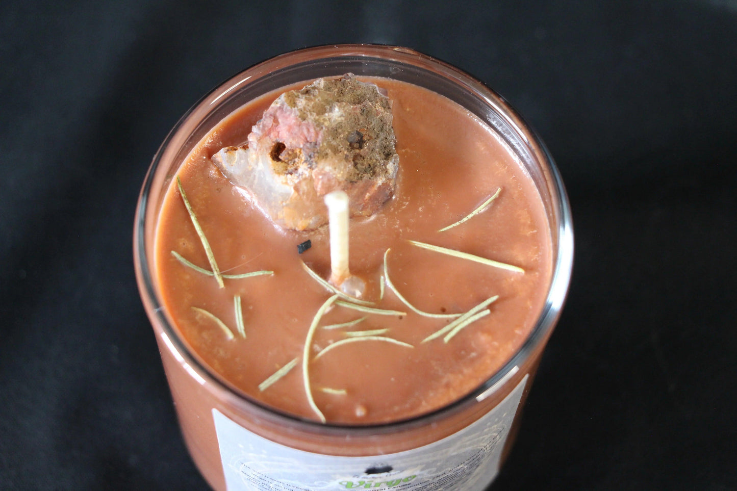 Hand-crafted crystal candle with herbs in glass jar on black background, Witches' Brew