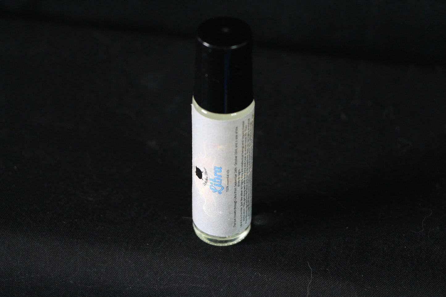 Handcrafted Libra essential oil roller bottle on black fabric background