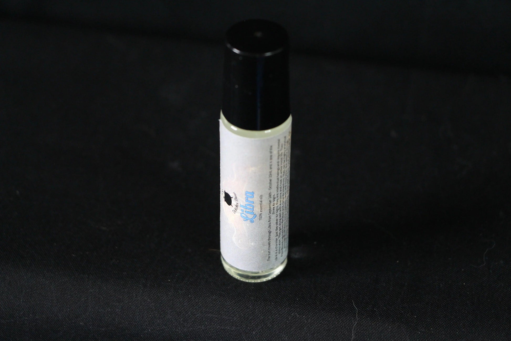 Handcrafted Libra essential oil roller bottle on black fabric background
