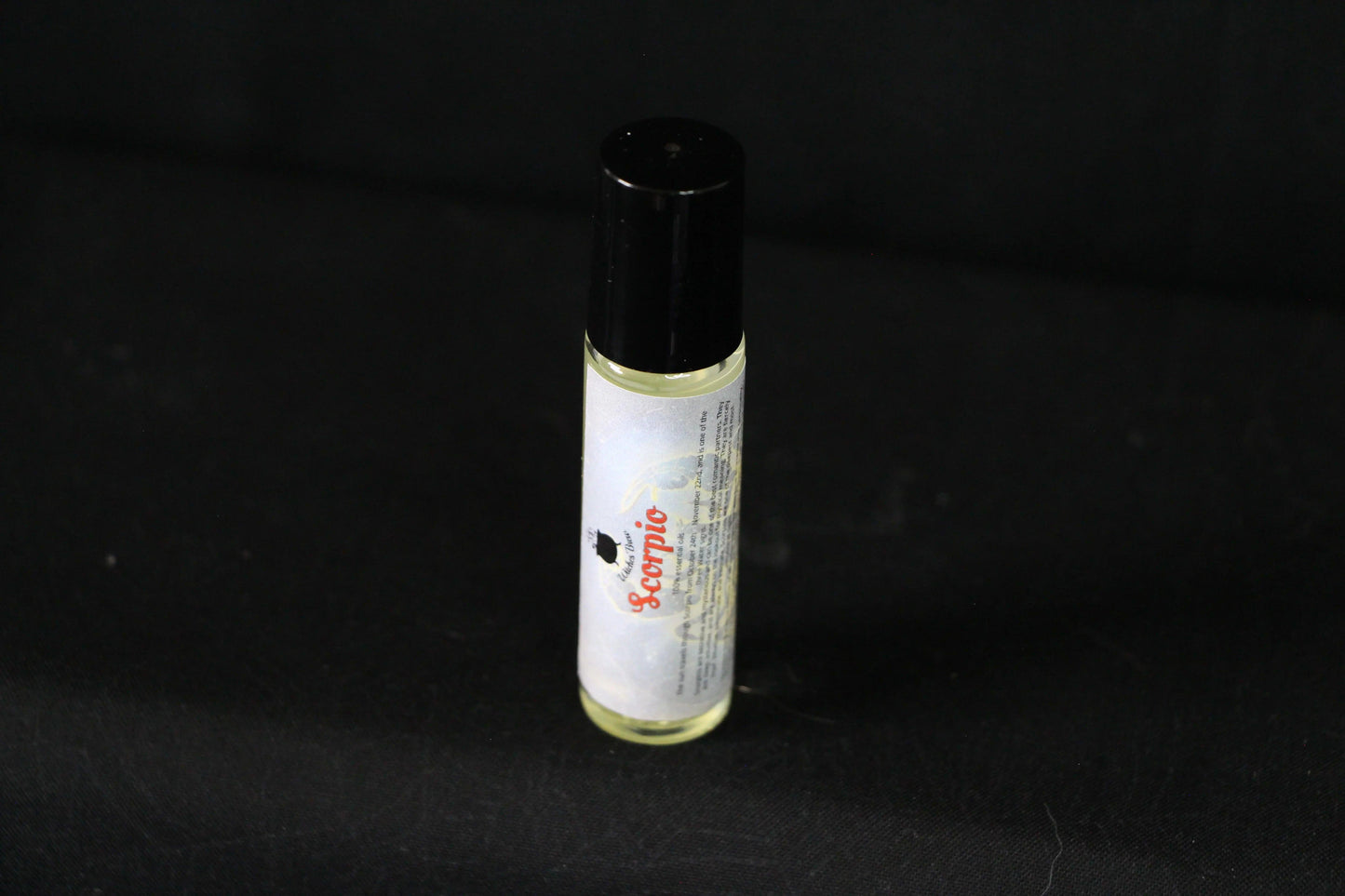 Scorpio essential oil roller bottle on black background, sustainable witch ritual tool