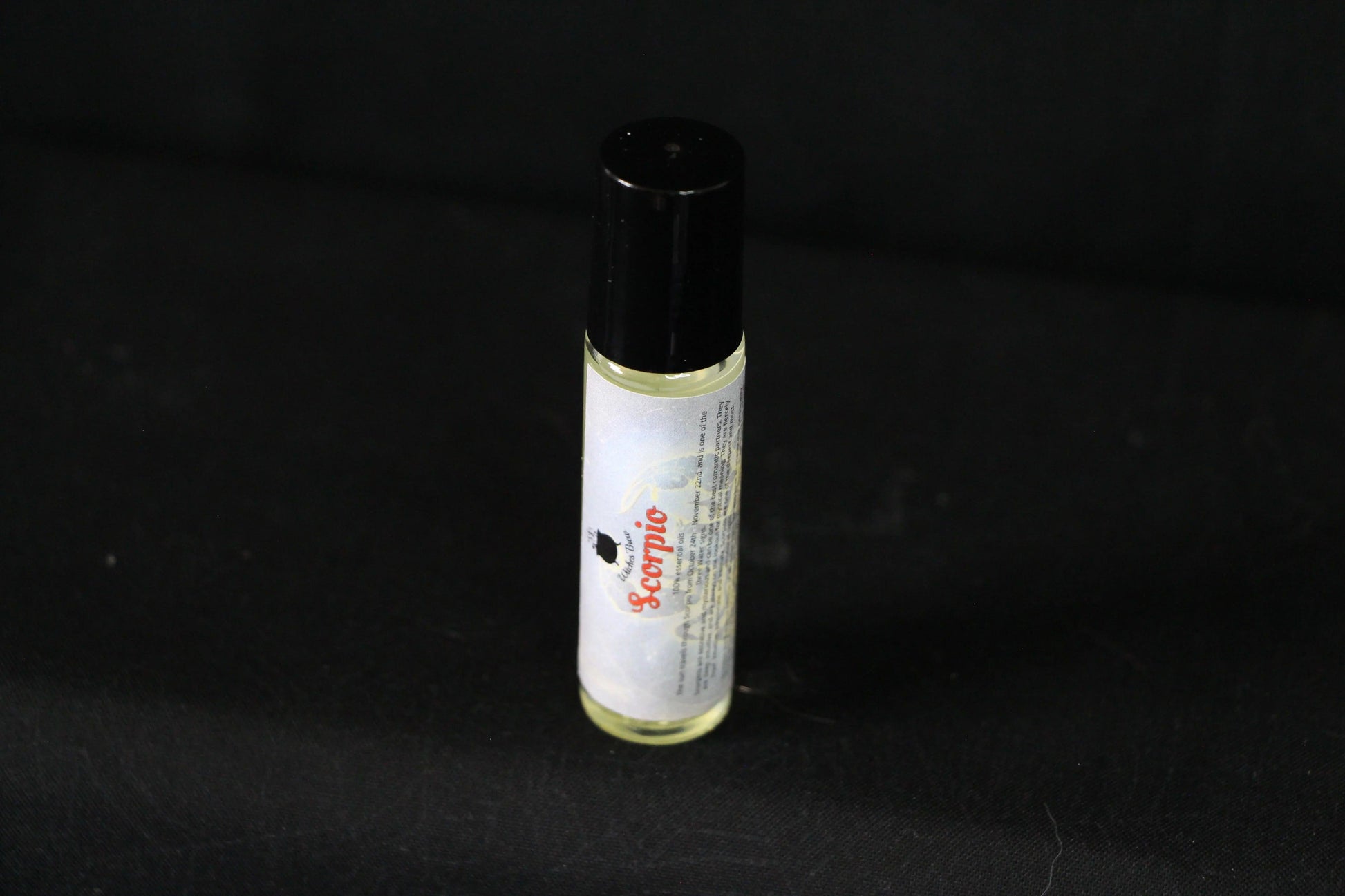 Scorpio essential oil roller bottle on black background, sustainable witch ritual tool