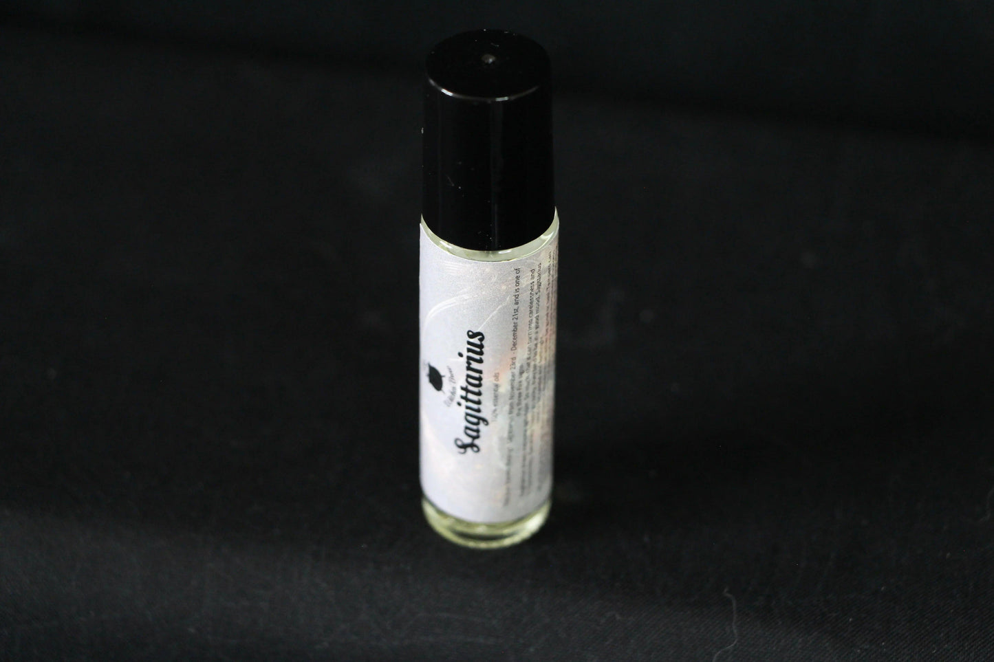 Sagittarius essential oil roller bottle on black background, sustainable hand-crafted ritual tool