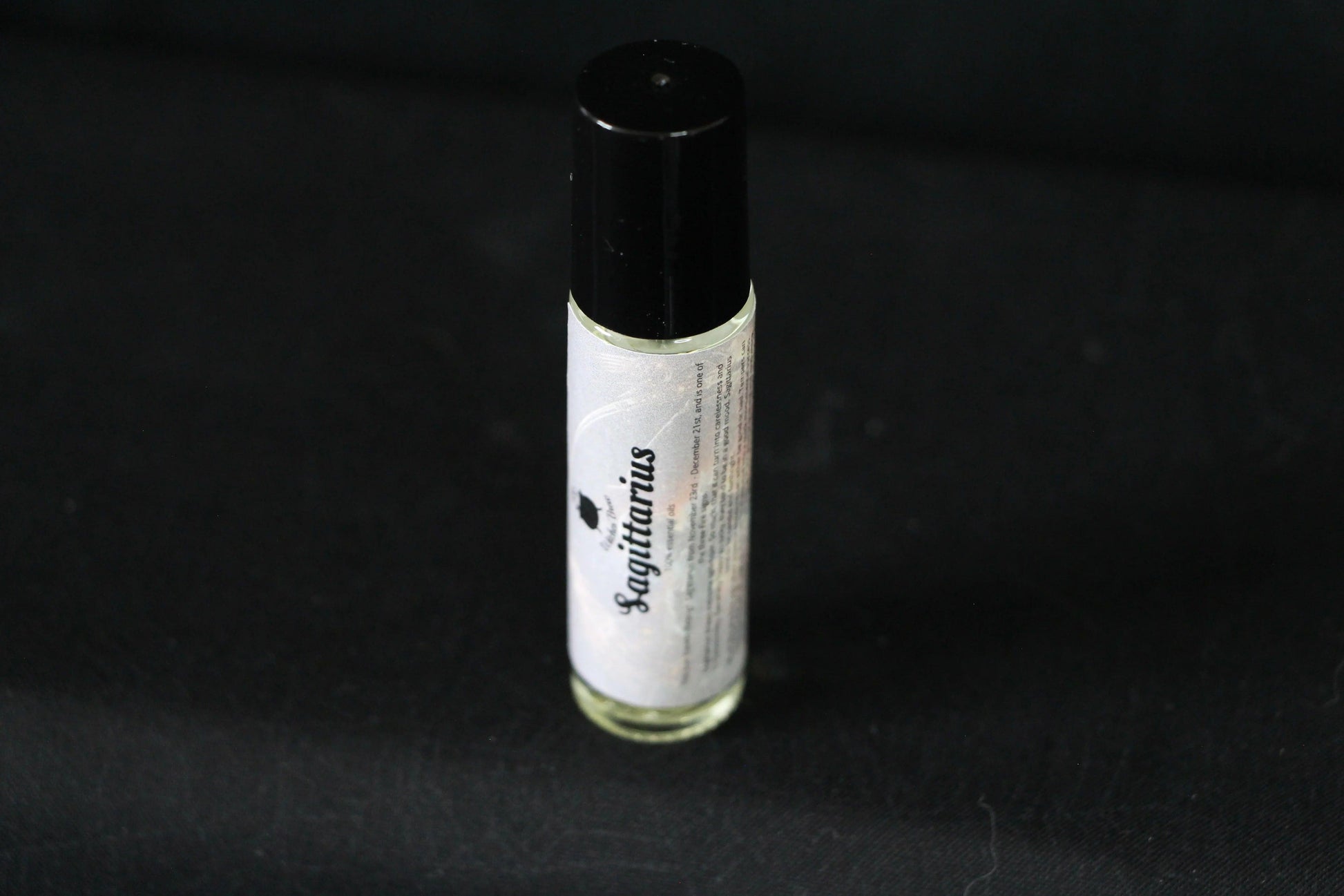 Sagittarius essential oil roller bottle on black background, sustainable hand-crafted ritual tool