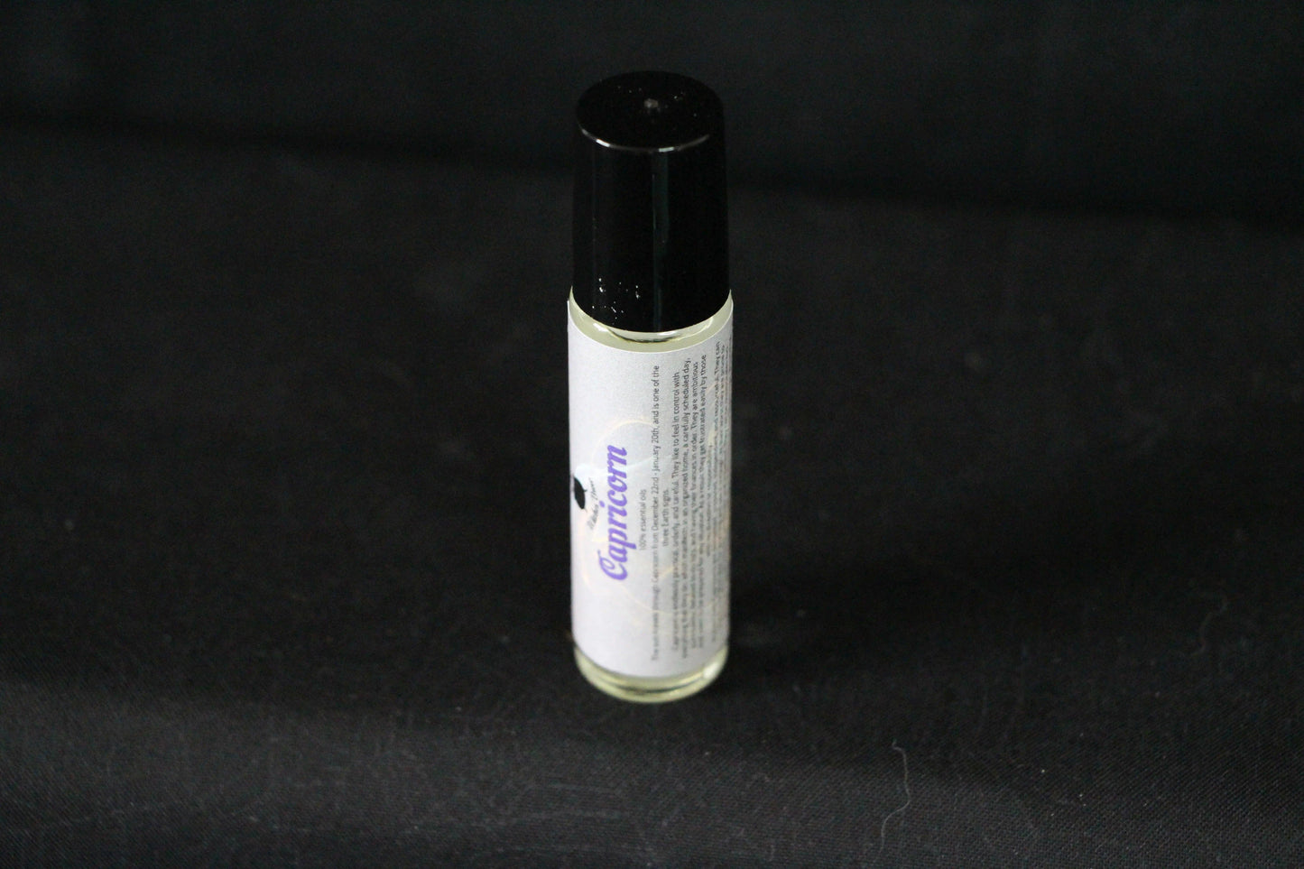 Capricorn essential oil roll-on bottle with black cap on a dark background