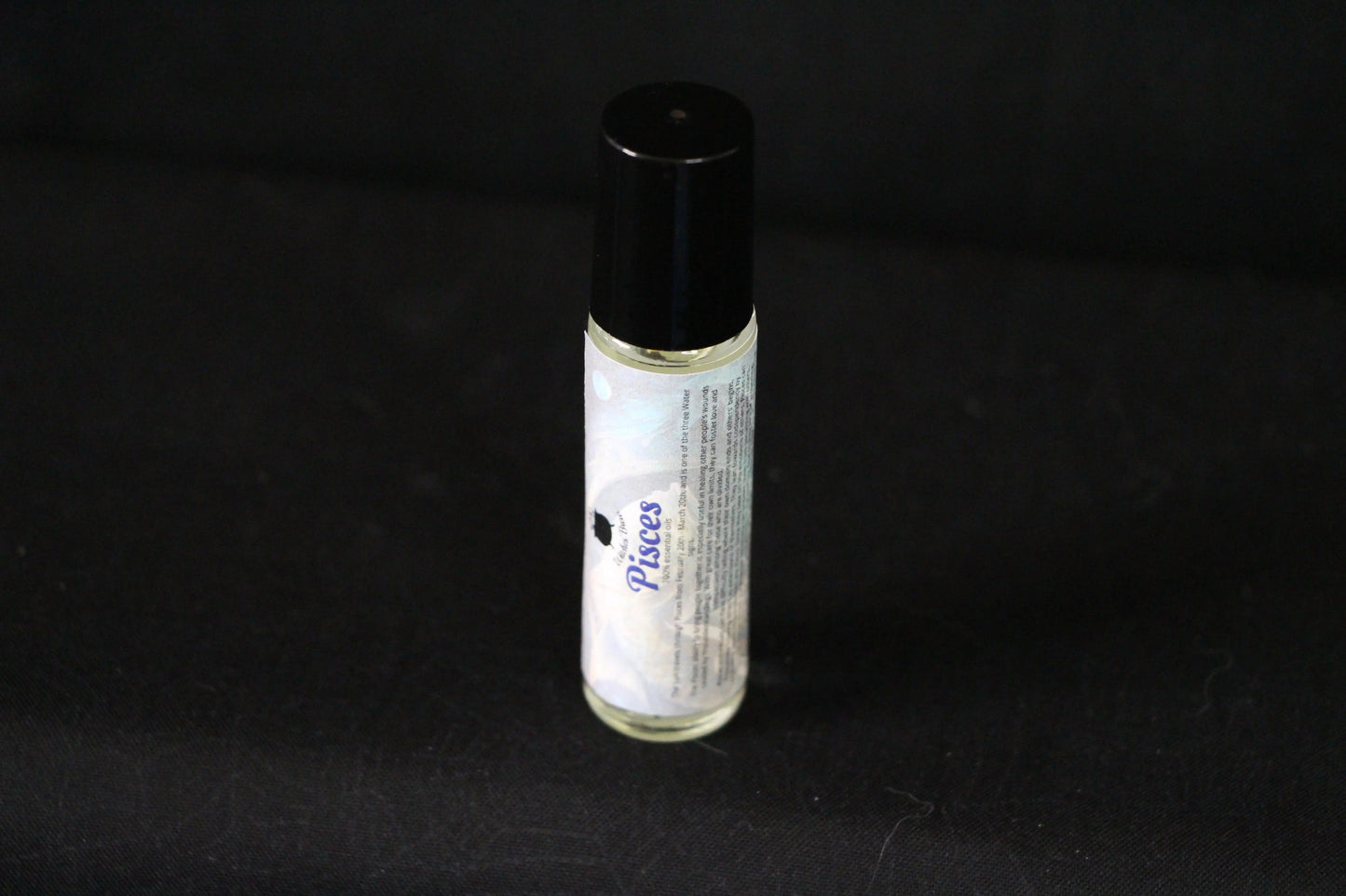 Pisces essential oil roll-on bottle on black background, sustainable witch ritual tool
