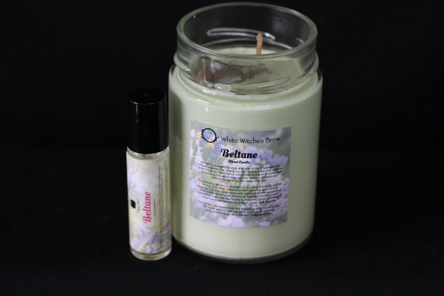 Beltane ritual candle and essential oil with floral label on black background