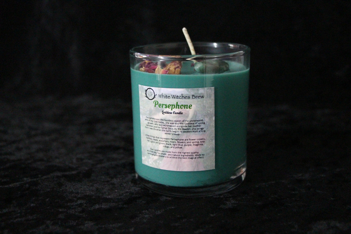 Hand-crafted teal crystal candle labeled Persephone by Witches' Brew on black velvet