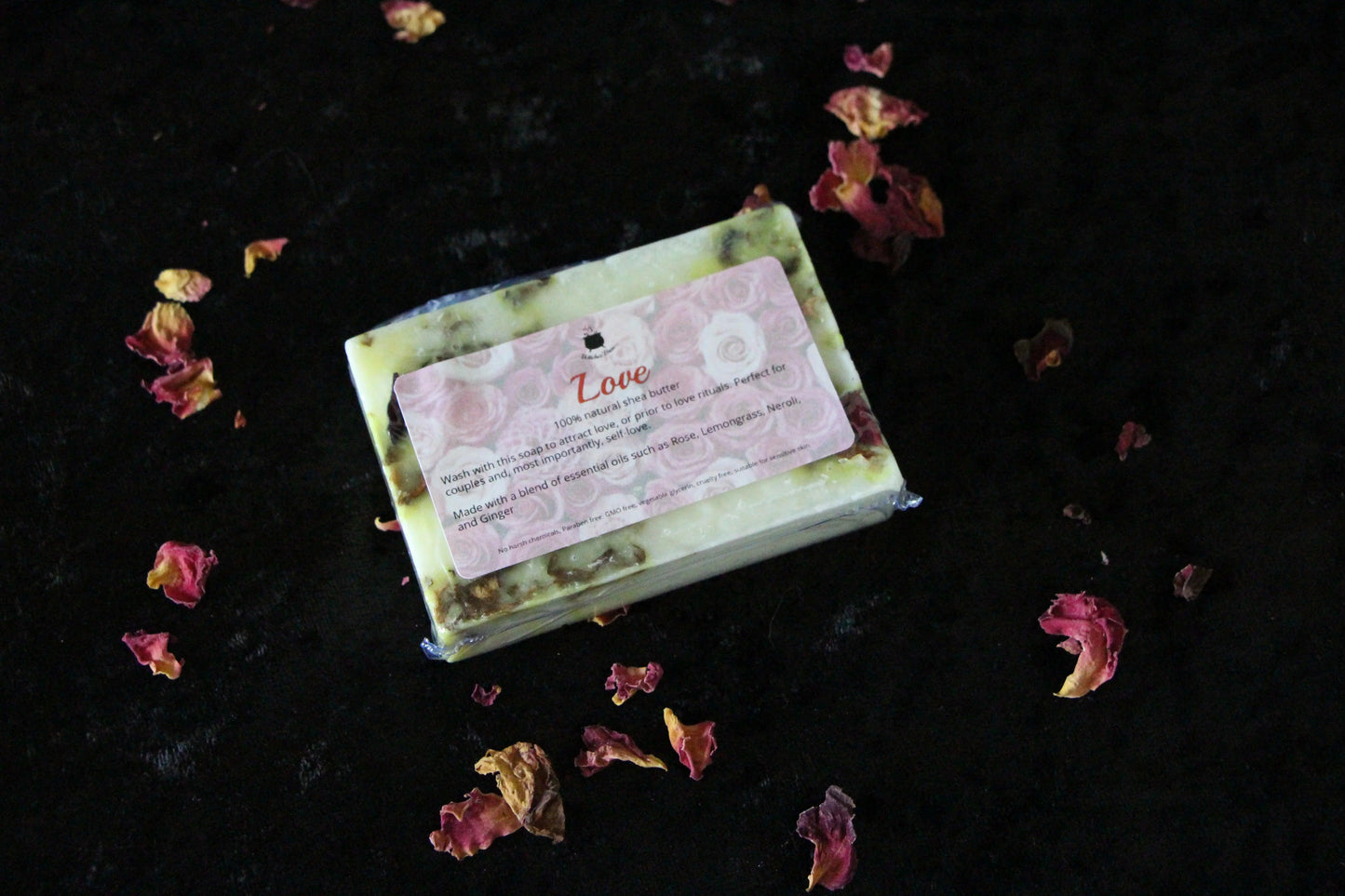 Handcrafted love ritual soap with rose petals on black background, sustainable witch goods