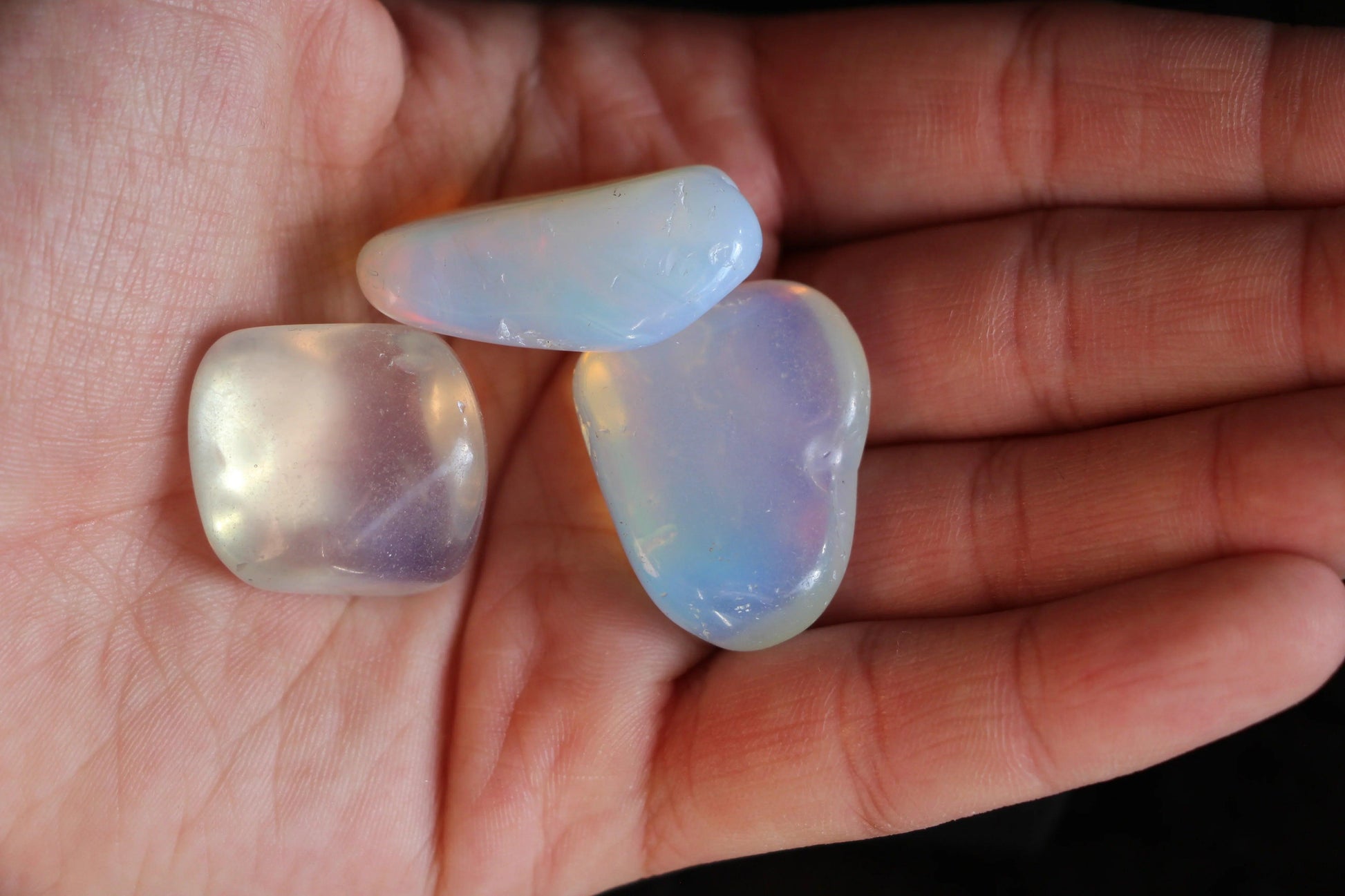 Opalite tumbled stones for modern witch rituals, displayed on a hand