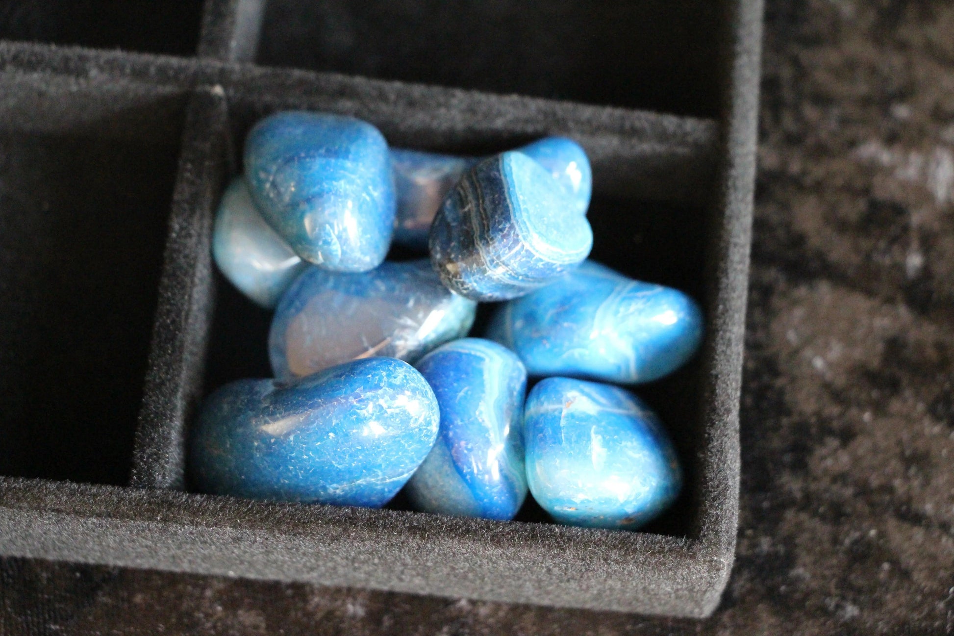 Blue tumbled crystals in a black velvet tray, ideal for modern witch rituals and intention setting.