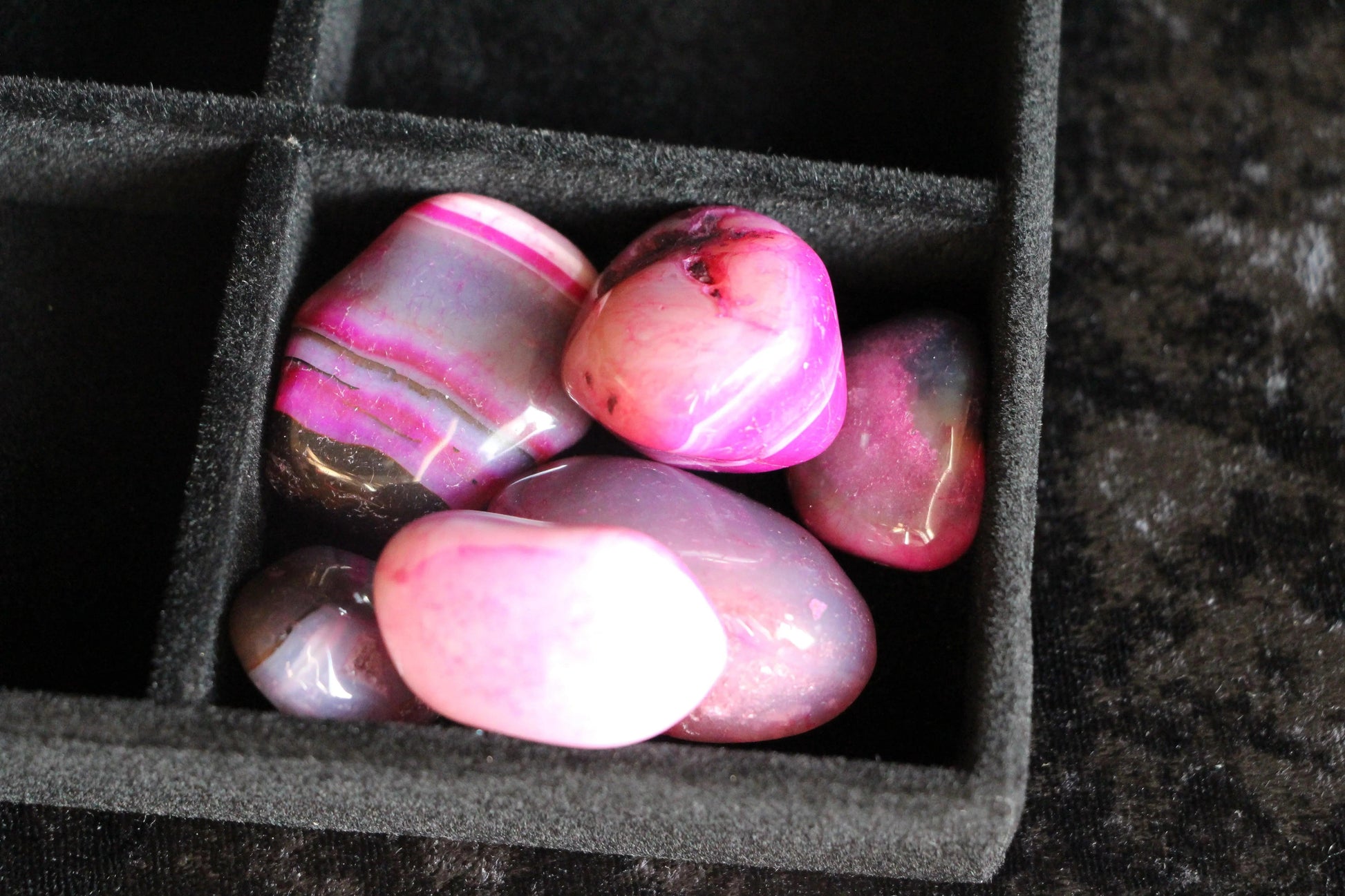 Pink polished crystals in black velvet tray for modern witch rituals
