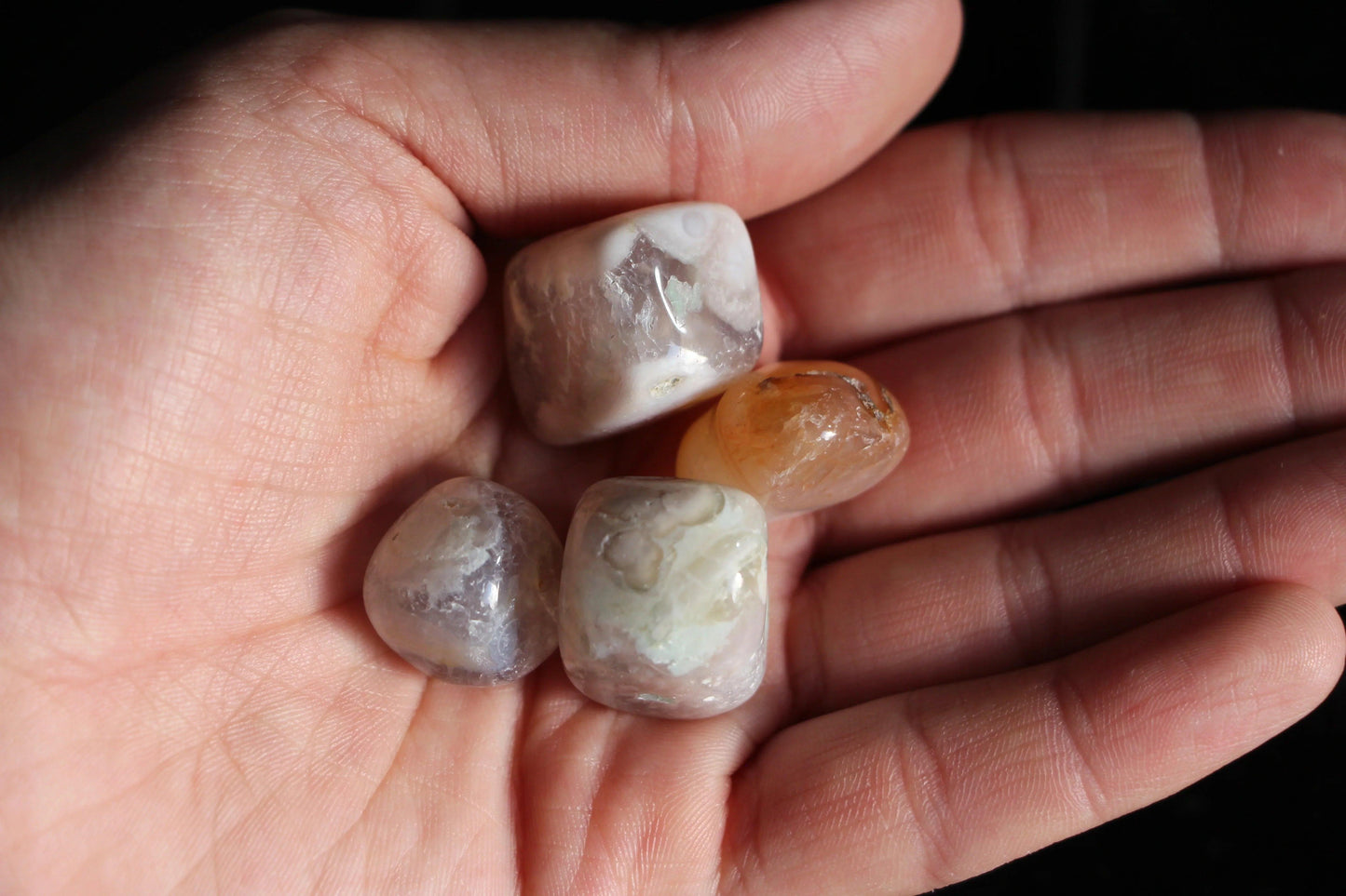 Hand holding polished crystal stones, sustainable witch ritual tool