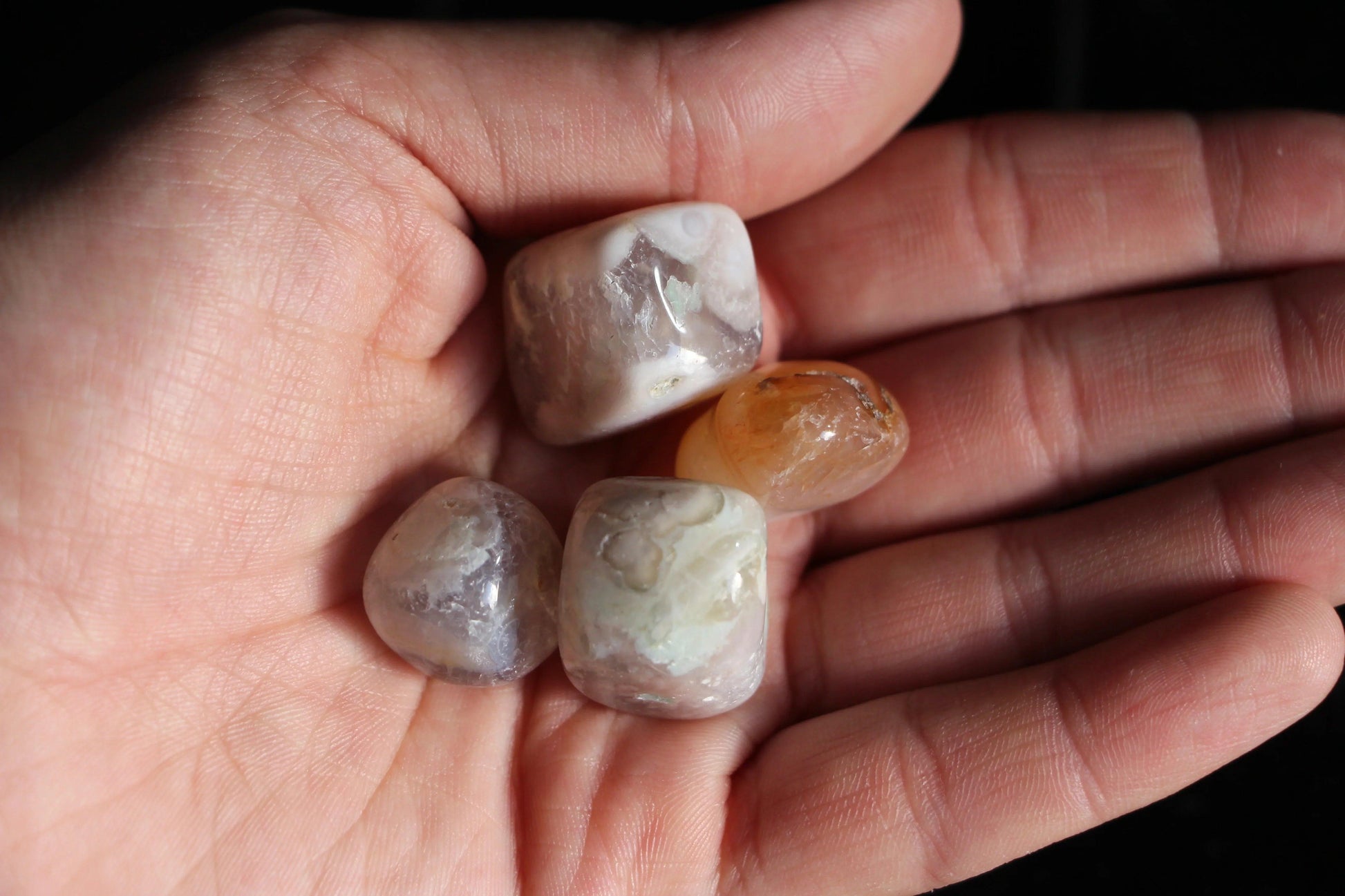 Hand holding polished crystal stones, sustainable witch ritual tool