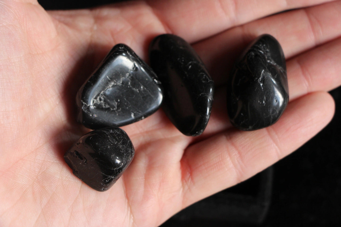 Hand holding polished black crystals, sustainable ritual stones for witches