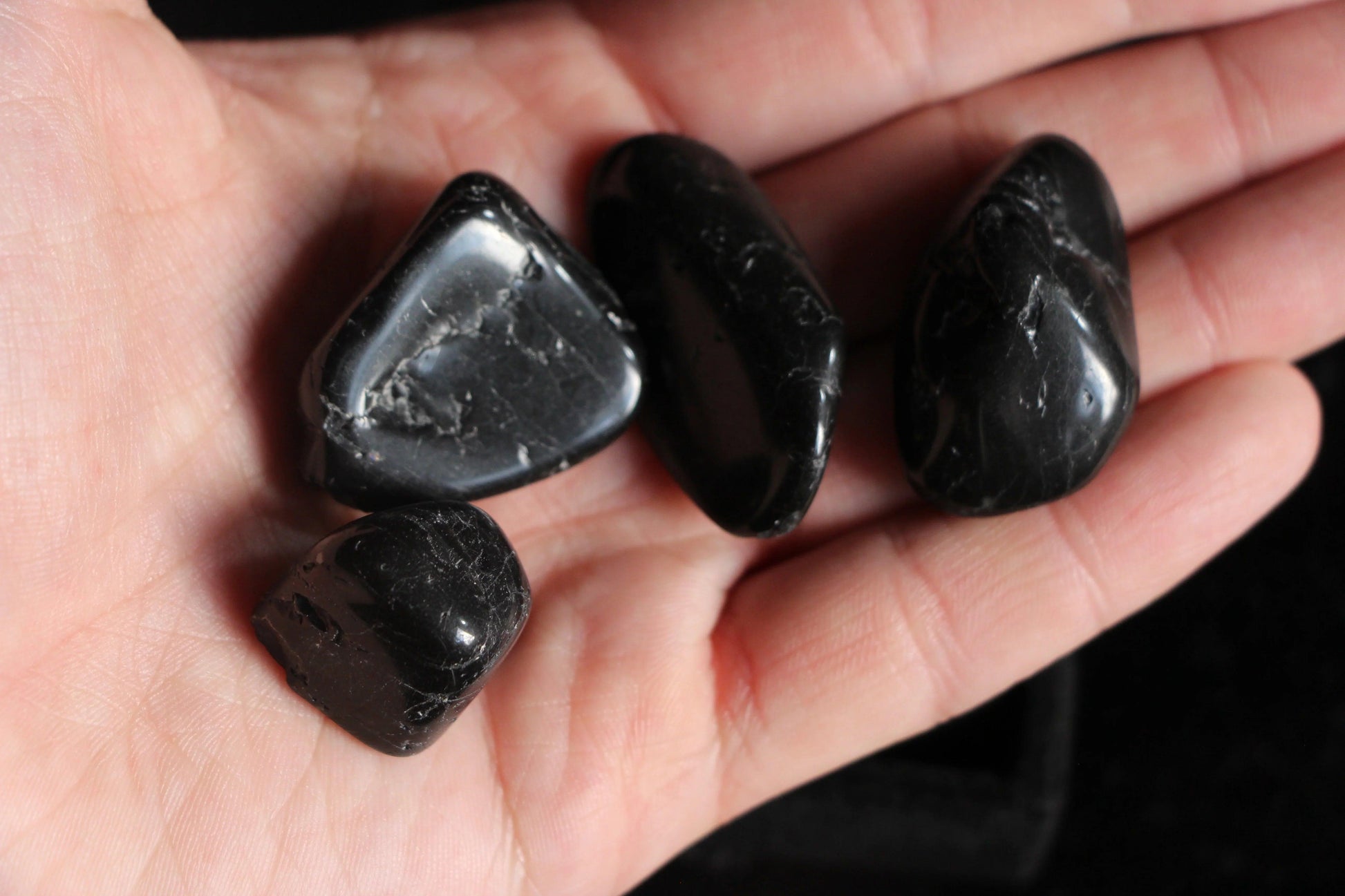 Hand holding polished black crystals, sustainable ritual stones for witches